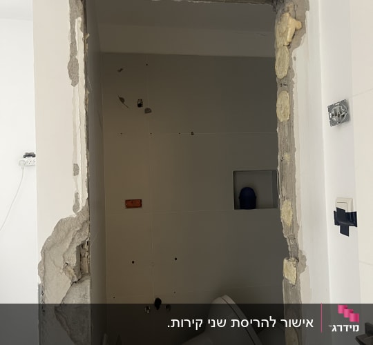 עבודות הריסה והרחבת פתח בקיר במהלך שיפוץ חדר שירותים